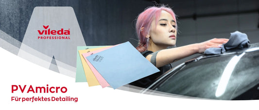 Eine junge Frau mit rosa Haaren reinigt mit einem grauen Mikrofasertuch die Oberfläche eines schwarzen Autos. Links im Bild ist das Logo „Vileda Professional“ zu sehen, darunter liegt ein Fächer farbiger Reinigungstücher. Text im Bild: „PVAmicro – Für perfektes Detailing“.