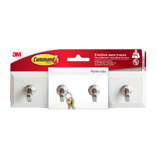 Die Command™ Schlüsselleiste in Quarz (HOM18-Q, 1 Stück) der 3M Deutschland GmbH mit vier Metallhaken ist in ihrer meist weiß-roten Verpackung abgebildet und hält einen Schlüsselbund an einem Haken.