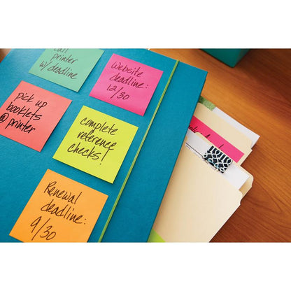 Na stole leží modrá složka vedle spisových složek a Post-it® Notes (76 mm x 127 mm, 100 listů/blok, 6 bloků/balení, 100% PEFC) od 3M Deutschland GmbH, na kterých jsou zaznamenány úkoly a termíny jako vyzvednutí brožur a kontrola referencí.