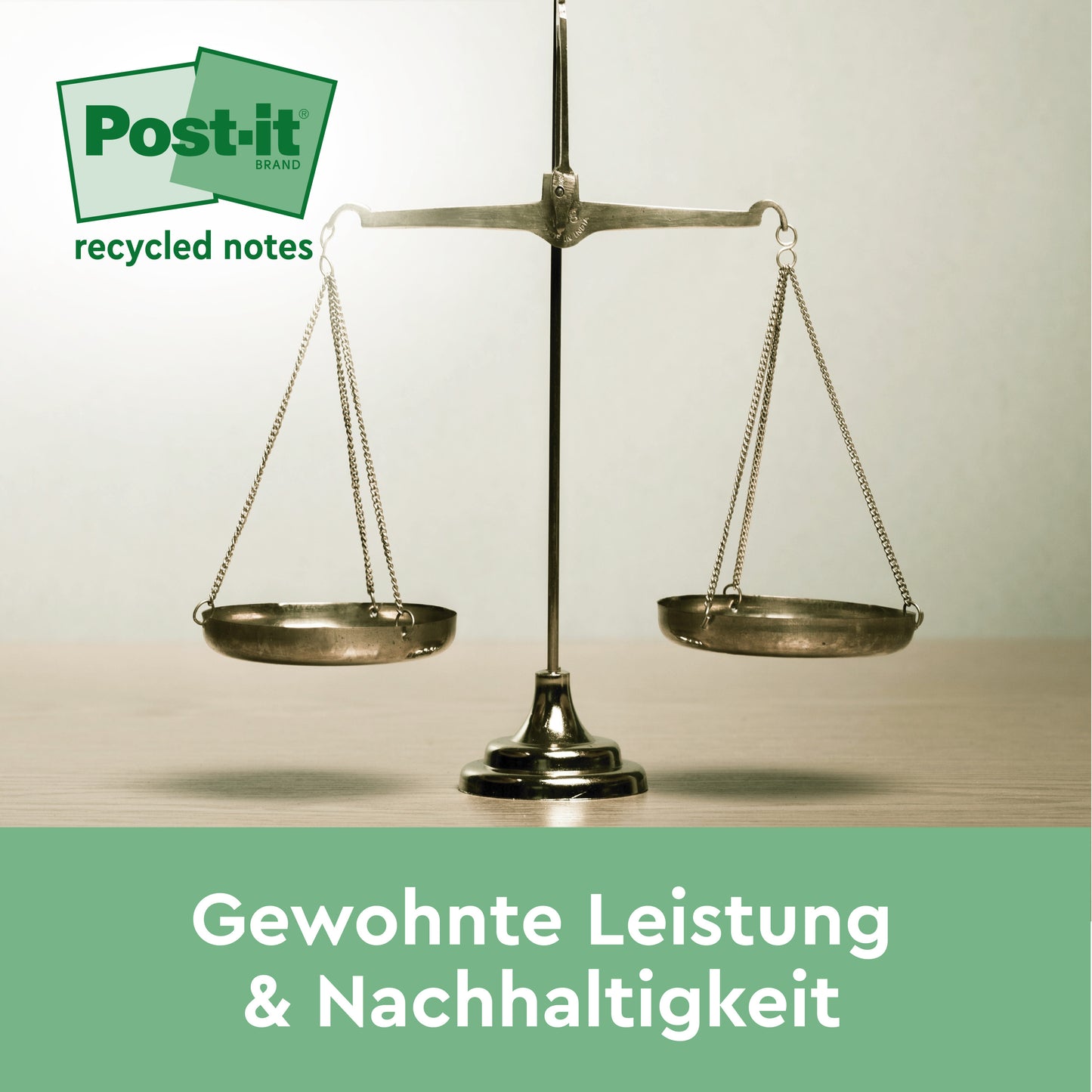 Na světlém povrchu stojí kovová váha. Nahoře je vidět logo Post-it® Super Sticky 100% recyklovaných poznámek od 3M Deutschland GmbH. Pod ním stojí německý text: "Obvyklý výkon & udržitelnost.