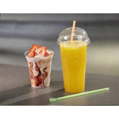 Průhledný kelímek s jahodovým parfaitem, nakrájenými jahodami a jogurtem stojí vedle vysokého Starpak smoothie kelímku z čirého PET s Starpak 50 Dom-víčkem „Hurricane“ (kulaté, Ø 9,5 cm – 4,5 cm); na šedém povrchu leží zelené míchátko.