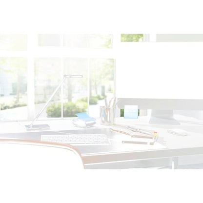 Moderní kancelářské uspořádání s černým 3M Post-it® Z-Notes Dispenser PRO se žlutými Post-it® Super Sticky Z-Notes (76x76 mm, 90 listů/blok), poznámkovými bloky, pery a lampou před velkými okny se slunečním světlem a zelenými stromy venku.