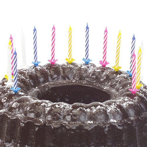 Čokoládový dort posypaný moučkovým cukrem a ozdobený deseti PAPSTAR narozeninovými svíčkami 6 cm, barevně tříděnými s držákem (od PAPSTAR GmbH) v různých barvách.