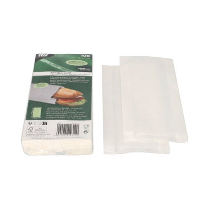 Stoh bílých PAPSTAR sáčků na chleba odolných proti tuku (21x10x3 cm) je zobrazen vedle zeleno-bílého balení společnosti PAPSTAR GmbH, které ukazuje sendvič a informace o produktu. Vedle balení (100 kusů) je několik smrštitelných sáčků částečně rozložených.