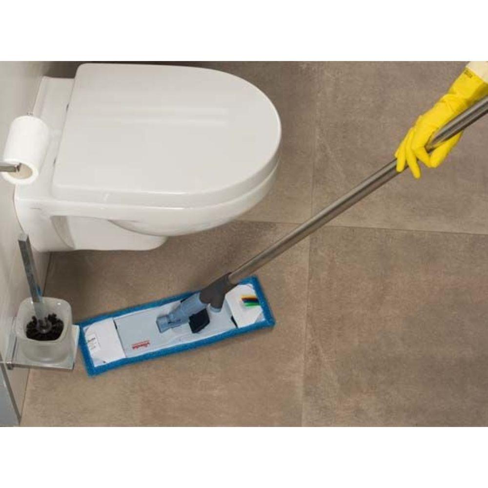 Osoba se žlutými rukavicemi účinně vytírá dlažbu v koupelně vedle bílé toalety pomocí držáku mopu Vileda Professional SprayPro z nerezové oceli od společnosti Vileda GmbH, který je vybaven podložkou s modrým okrajem. V blízkosti se nachází držák, ve kterém je uložena toaletní štětka.