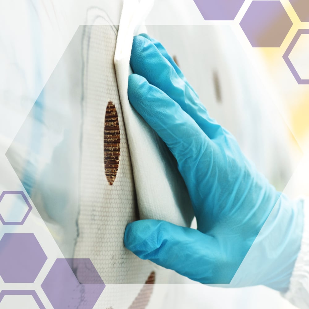 Rukavice čistí kruhovou hnědou skvrnu na bílé ploše s Kimtech® Science Precision ubrousky od Kimberly-Clark GmbH. Poloprůhledné šestiúhelníky jsou položeny přes obrázek.