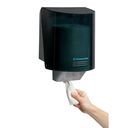 Ruka vytahuje papírový ručník z nástěnného dávkovače utěrek Kimberly-Clark Professional™ - centrální odběr v šedé barvě, který zajišťuje hygienický odběr utěrek. Značka: Kimberly-Clark GmbH. 1 dávkovač | Karton (1 dávkovač).