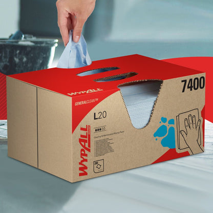 Ruka vytahuje čisticí utěrku WypAll® L20 General Clean z modré krabice BRAG™ od společnosti Kimberly-Clark GmbH, která obsahuje 280 listů, a pokládá ji na hladký povrch.