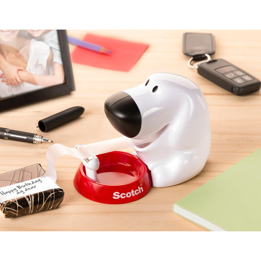 Der Scotch™ Tischabroller im Hunde Design C31 mit Scotch® Magic™ Klebeband (19 mm x 8,89 m) von 3M Deutschland GmbH steht auf einem Holzschreibtisch neben Notizbuch, Stift, Schlüsselanhänger, Geschenk und gerahmtem Foto.