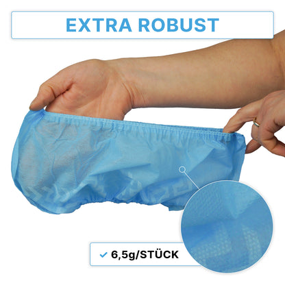 Eine Hand hält einen blauen ARNOMED ABS Schuhüberzieher, rutschfest, Einweg von ARNOWA GmbH mit einem strukturierten Muster. Oben steht der Text "EXTRA ROBUST" und darunter "6,5g/STÜCK", dazu eine Nahaufnahme des Schuhüberzugsmaterials. Beutel enthält 100 Stück.