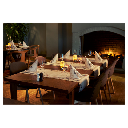 Útulná jídelní oblast obsahuje dva dřevěné stoly s vinnými sklenicemi a ubrousky Duni Bio Dunisoft® vedle blikajících svíček. Tmavé židle obklopují stoly, vylepšené hořícím krbem. Plyšové sedací soupravy a rostlina přispívají k designu inspirovanému přírodou.