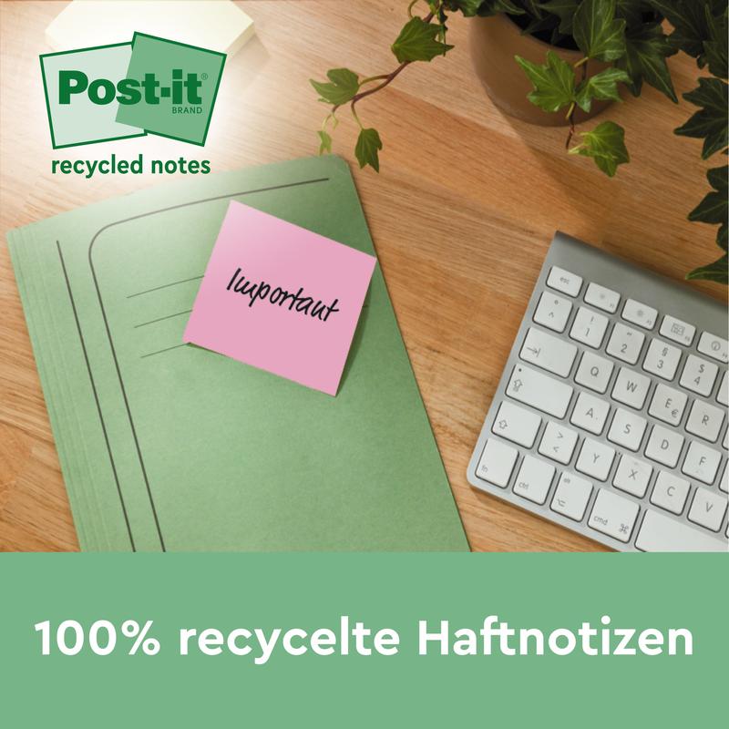 Zelená složka s růžovým recyklovaným lístkem Post-it® od 3M Deutschland GmbH (38 mm x 51 mm, 100 listů/blok, 100% PEFC) leží na dřevěném stole vedle bílé klávesnice a pokojové rostliny.