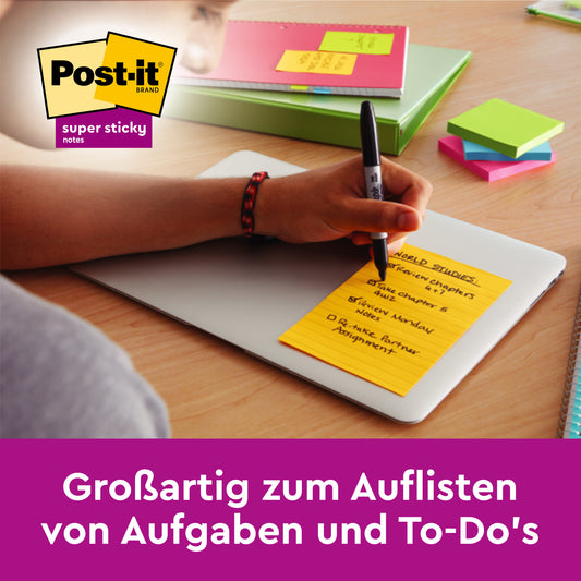 Eine Person schreibt eine To-Do-Liste auf einem bunten, linierten Post-it® Super Sticky Note (101mm x 152mm) von 3M Deutschland GmbH, das auf einem geschlossenen Laptop liegt. Weitere Zettel und Schreibwaren liegen auf dem Schreibtisch. Perfekt zum Organisieren von Aufgaben und To-Dos!.