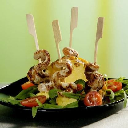 PAPSTAR grilovací špízy 21 cm "Golf" od PAPSTAR GmbH: Perfektní BBQ a grilovací párty špízy z kuřete a ananasu na čerstvých salátech s cherry rajčaty, podávané na černém talíři před zeleno-žlutým pozadím. 250 kusů v papírovém tácku.