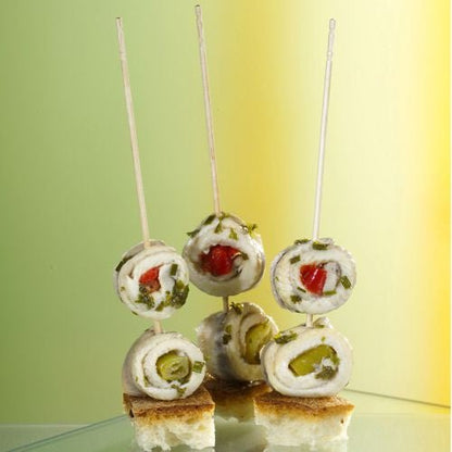 Tři srolované rybí filety na špejli stojí vzpřímeně na kostkách chleba, prezentovány jako PAPSTAR Fingerfood-Picker "pure" 15 cm (soustružené, elegantní) od PAPSTAR GmbH - ideální pro stylové cateringové akce.