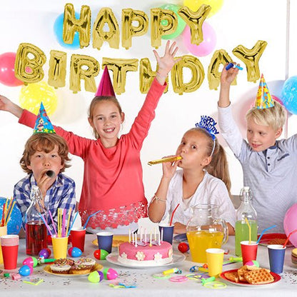 Čtyři děti s party čepičkami sedí u slavnostně prostřeného stolu s dortem a nápoji. Na stěně se fóliové balónkové sety „Happy Birthday“ společnosti PAPSTAR GmbH postarají o zlatý lesk na narozeninové oslavě.