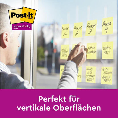 Osoba lepí Post-it® Super Sticky Notes, žluté (76x127 mm) od 3M na skleněnou desku. Perfektní pro vertikální povrchy - 90 listů/blok, 14 bloků + 2 zdarma, 100% PEFC. Ideální jako poznámkové nebo lepící papírky.