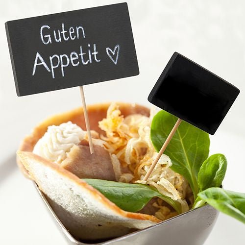 Malá miska obsahuje rolovaný plátek masa, zeleninu, křupavou cibuli a smetanu. Dva PAPSTAR Fingerfood-Picker 8,5 cm (černé, balení po 20 kusech) od společnosti PAPSTAR GmbH jsou ideálním doplňkem pro každou sbírku příslušenství pro bufety nebo večírky.