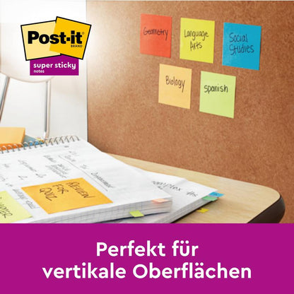 Korková deska drží Post-it® Super Sticky Z-Notes (76 x 76 mm, různé barvy, 90 listů/blok) od 3M s oddíly „Geometrie“, „Jazykové umění“ atd. Více lepících lístků a učebních materiálů je na stole. Perfektní pro vertikální povrchy.