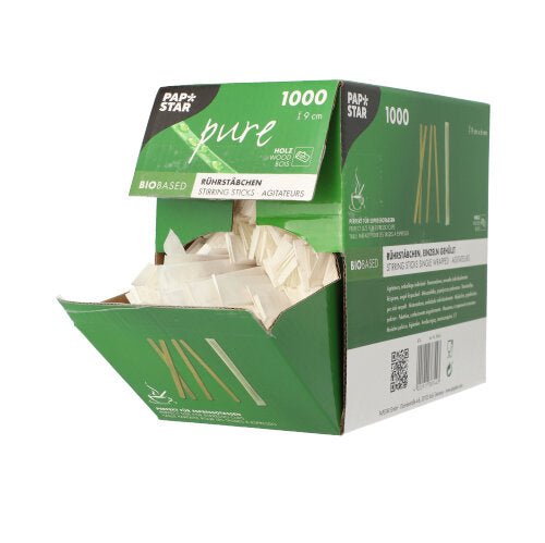 Otevřená zeleno-bílá krabice s PAPSTAR 1000 míchacími tyčinkami, dřevo „pure“, jednotlivě zabalené od PAPSTAR GmbH ukazuje ekologické, jednotlivě balené dřevěné míchací tyčinky na bílém pozadí. Krabice je označena pro 1000 kusů.