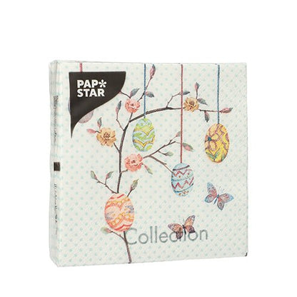 Čtvercové balení s 20 ubrousky společnosti PAPSTAR GmbH, 25 cm x 25 cm, 3-vrstvé, ukazuje etiketu a zdobená velikonoční vajíčka na větvích s květinami a motýly na světle modrém puntíkovaném pozadí.