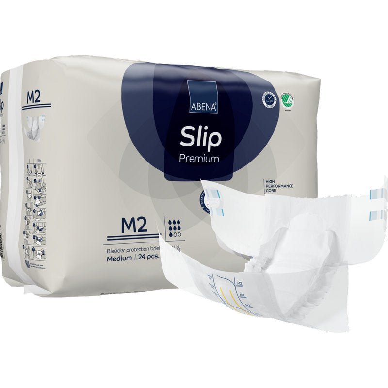 Za rozloženou plenkou je zobrazeno balení ABENA Slip Premium od Abena Re-Seller GmbH, velikost M2. Na obalu je uvedeno, že obsahuje 24 středně velkých slipů pro spolehlivou inkontinenční péči.