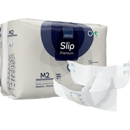 Za rozloženou plenkou je zobrazeno balení ABENA Slip Premium od Abena Re-Seller GmbH, velikost M2. Na obalu je uvedeno, že obsahuje 24 středně velkých slipů pro spolehlivou inkontinenční péči.
