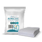 Balení jednorázových mycích rukavic Altruan Altrucare CuraSOFT Basic (60g) s 50 rukavicemi je zobrazeno vedle hromady nesložených rukavic. Balení ukazuje, že každá rukavice je velká 22 cm x 15 cm.