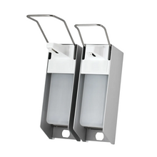 Vystaveny jsou dva nástěnné dávkovače AMPri pro 500 ml dezinfekčního prostředku a mýdla, s pouzdrem z nerezové oceli a bílým plastovým dávkovačem. Každý je vybaven dlouhou pákou pro hygienické dávkování. Jsou umístěny vedle sebe před jednoduchým bílým pozadím.