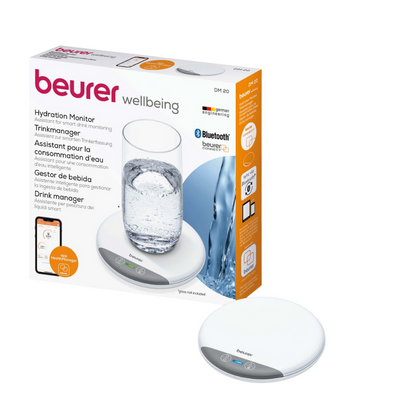 Obrázek ukazuje Beurer DM 20 Hydratační monitor Trinkmanager ve svém balení. Krabice prezentuje produkt vedle sklenice vody a zdůrazňuje jeho Bluetooth konektivitu. Zařízení je malé, bílé kulaté podložky se dvěma dotykovými tlačítky a snadno se integruje s beurer HealthManager Pro.