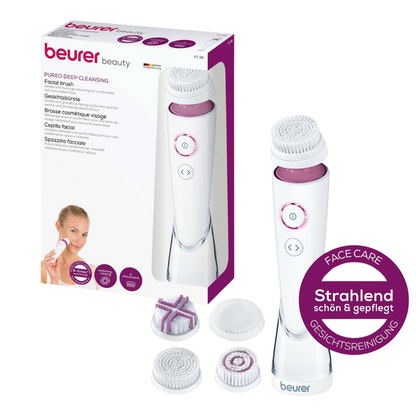 Obrázek ukazuje zabalenou Beurer FC 95 obličejovou kartáč Pureo Deep Cleansing Set od Beurer GmbH. Sada obsahuje hlavní zařízení pro obličejový kartáč, tři různé kartáčové hlavy, které jsou vhodné pro každý typ pleti, a malý fialový kulatý štítek, který zdůrazňuje hloubkově čistící účinek péče a čištění obličeje.