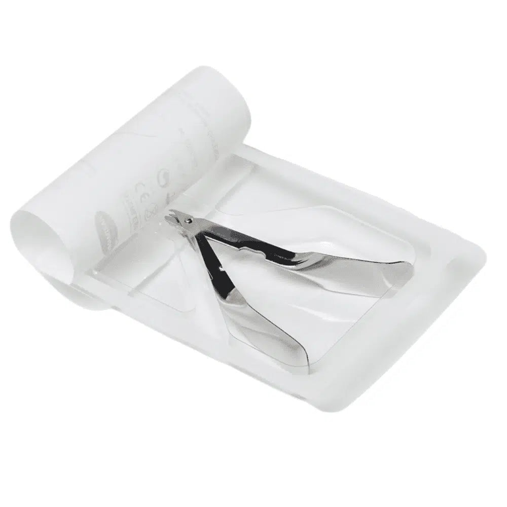 Výprodejový artikl: Odstraňovač svorek Hartmann 10 cm od Paul Hartmann AG leží na bílém jednorázovém tácku s vedle ležícím srolovaným papírovým listem, což naznačuje použití v lékařské nebo manikúrní oblasti. (Balení: 1 kus).