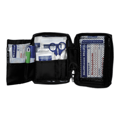 Otevřená lékárnička Holthaus Medical TRAVEL modrá/červená se zipem od společnosti Holthaus Medical GmbH & Co. KG ukazuje různé předměty první pomoci. Mezi předměty patří nůžky, náplasti, alkoholové tampony, gázové obklady a zelená pastelka. Síťová kapsa na pravé straně obsahuje další náplasti a brožuru první pomoci pro rychlé nahlédnutí.