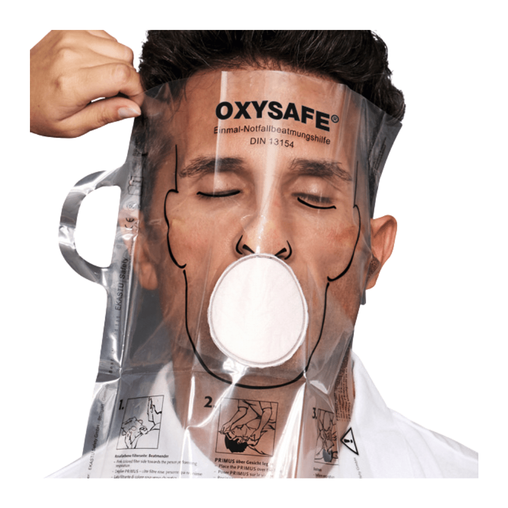 Osoba má nasazenou průhlednou masku Holthaus Oxysafe® pro nouzové dýchání od společnosti Holthaus Medical GmbH & Co. KG a má zavřené oči, zatímco jiná osoba masku přizpůsobuje. Výrobek je opatřen pokyny a diagramy, které jsou vytištěny na plastovém povrchu.