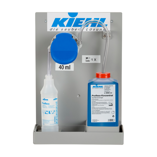 Eine wandmontierte Johannes Kiehl KG Kiehl-DosiExpress 25 ml Pumpe für Desinet-compact Konzentrat oder Blutoxol, mit transparentem Schlauch, einer 1L "Profess"-Flasche und einer 2L blauen "Profess-Konzentrat" oder Desinet-compact Flasche.