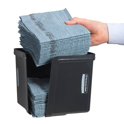 Ruka vkládá čtvrtinově složené ubrousky do šedého dávkovače Kimberly-Clark Professional™ od Kimberly-Clark GmbH - pro hygienické vyjmutí ubrousků. Úhledně složené ubrousky a přední etiketa jsou viditelné.