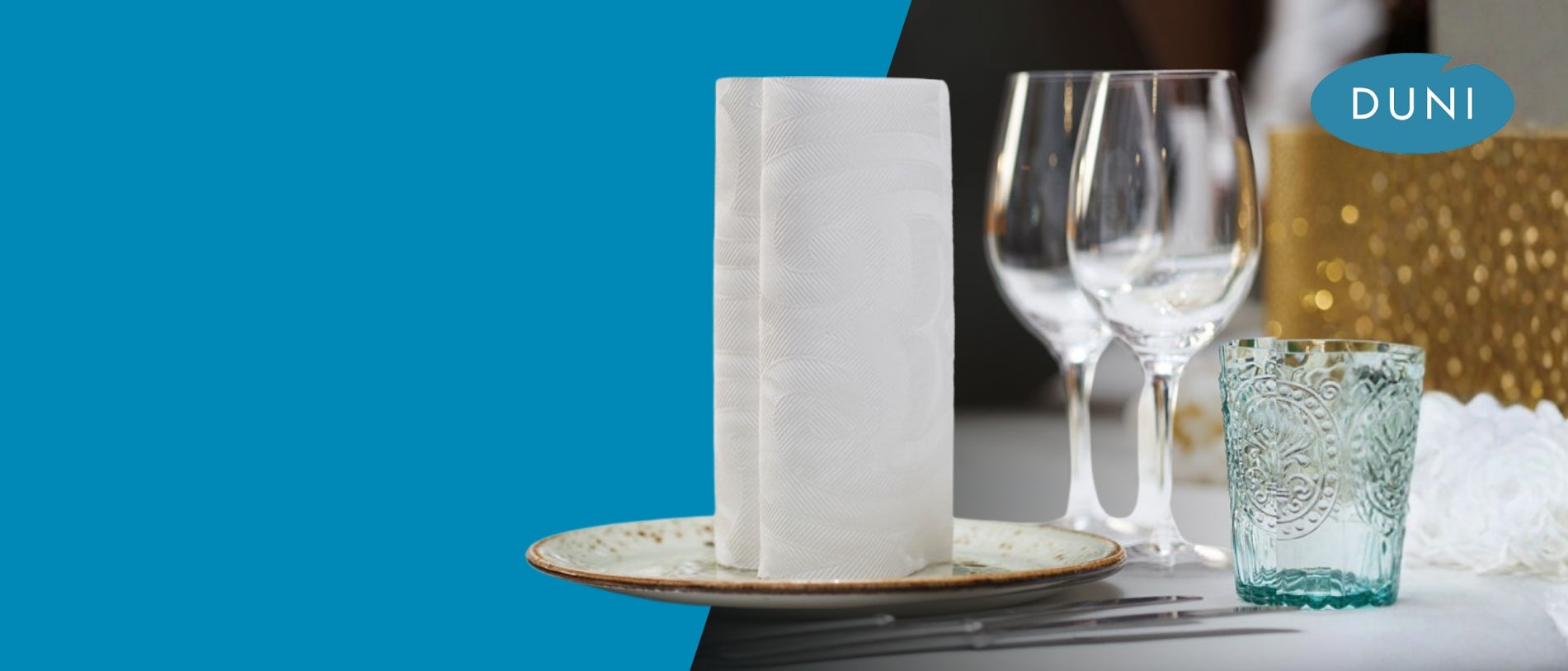 Banner mit weißer DUNI-Serviette auf einem Teller vor gedecktem Tisch mit Wein- und Wassergläsern; links große türkisfarbene Fläche, rechts unscharfer festlicher Hintergrund mit DUNI-Logo oben rechts.