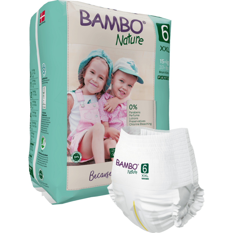 Zobrazeno je balení Bambo Nature Pants od společnosti Abena Re-Seller GmbH pro děti nad 15 kg se dvěma smějícími se dětmi v kloboucích a lacláčích na balení. V popředí je vidět jednotlivá plena.