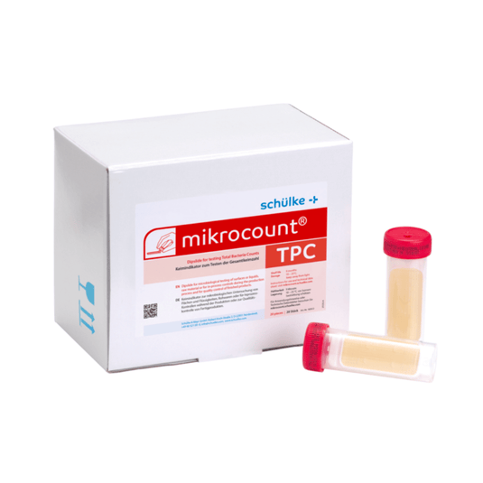 Bílá krabička s nápisem „Schülke & Mayr GmbH Mikrocount® TPC, živná půda | balení (20 kusů)“ s logem a popisem produktu vedle dvou lahviček pro mikrobiální testy, z nichž jedna má žluté víčko a druhá průhledné víčko.