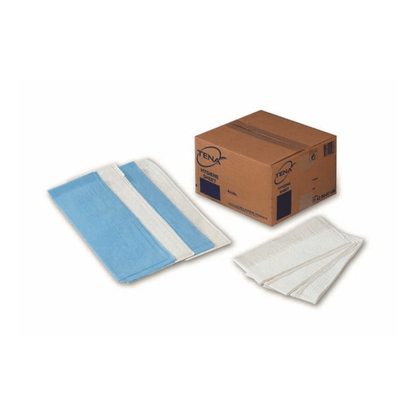 Krabice s nápisem "TENA - Essity Germany GmbH" stojí vedle stohů modrých a bílých TENA Hygiene Sheet nahrazující artikul č. 774454 (balení 100 kusů), přičemž několik vložek je rozložených, aby ukázaly svou velikost, strukturu a savý povrch.