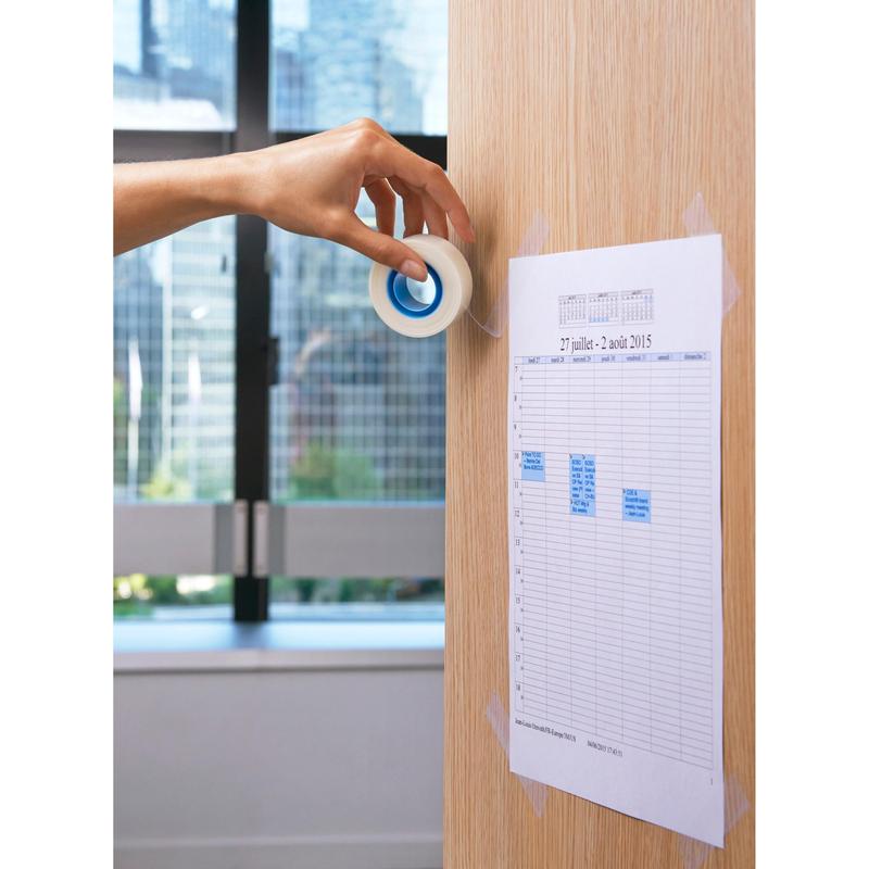 Ruka používá Scotch® neviditelnou lepicí pásku (19 mm x 33 m) od společnosti 3M Deutschland GmbH k připevnění vytištěného plánu na světlou dřevěnou stěnu. V pozadí okno poskytuje výhled na městskou kulisu.