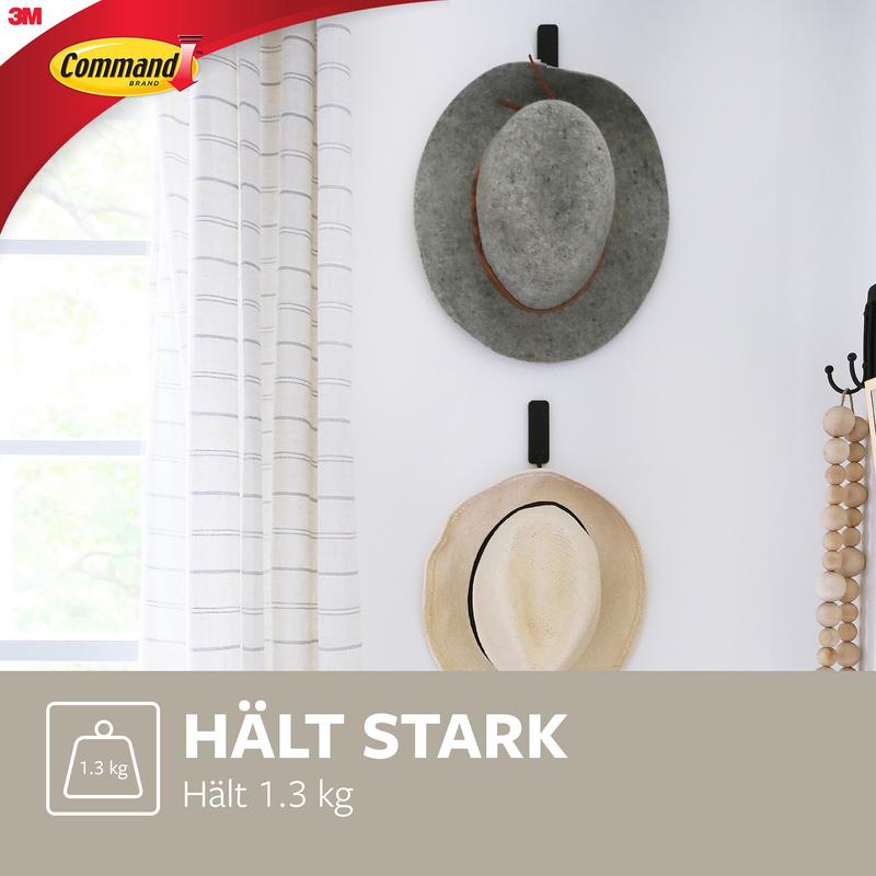 Dva klobouky, jeden šedý a jeden béžový, visí na středně velkém matně černém háčku Command™ (17034B) vedle okna s bílými závěsy. Tyto nástěnné háčky od 3M unesou až 1,3 kg a chrání vaše stěny.