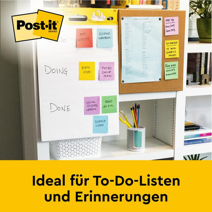 Na stole leží Post-it® Super Sticky samolepicí Mini Meeting Chart, 38x45,7cm, od 3M Deutschland GmbH, s barevným seznamem úkolů. V blízkosti leží modrý diář a knihy zaplňují polici pod ním. Text: "Ideální pro seznamy úkolů a připomínky.