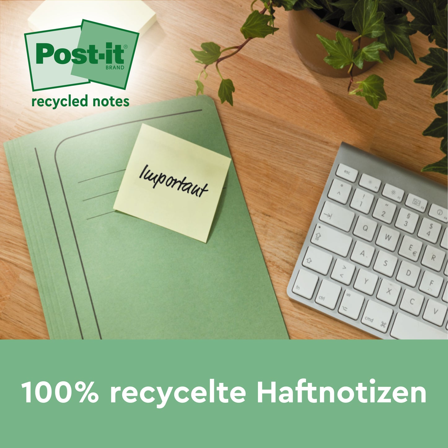 Zelená složka se žlutým Post-it® Super Sticky 100% recyklačním lístkem (47,6 x 47,6 mm, 70 listů/blok, PEFC) od 3M Deutschland GmbH s nápisem "důležité" leží na dřevěném stole vedle klávesnice a rostliny. Text je v němčině.