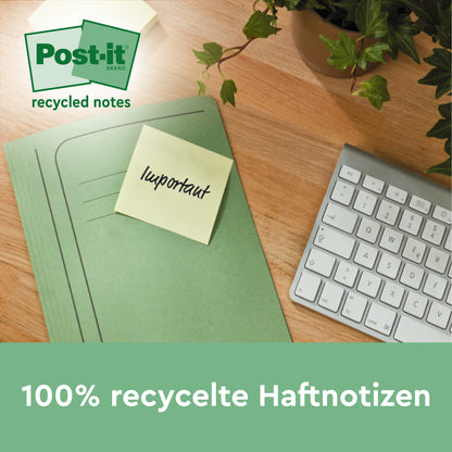 Zelená složka se žlutým Post-it® Super Sticky 100% recyklačním lístkem (47,6 x 47,6 mm, 70 listů/blok, PEFC) od 3M Deutschland GmbH s nápisem "důležité" leží na dřevěném stole vedle klávesnice a rostliny. Text je v němčině.