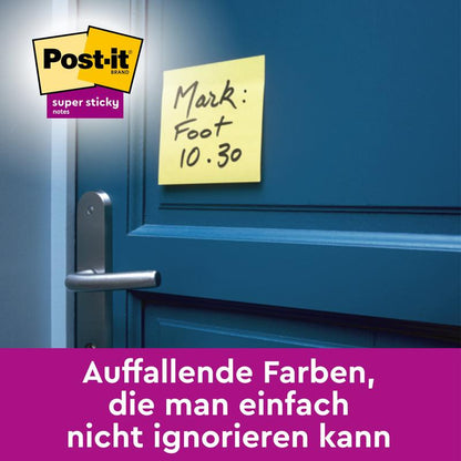 Žlutý Post-it® Super Sticky Note (47,6 mm x 47,6 mm, 90 listů/blok) od 3M Deutschland GmbH je umístěn poblíž modré kliky dveří. Na papírku je napsáno "Mark: Fuß 10.30". Nahoře je vidět logo, dole německý text o výrazných barvách.